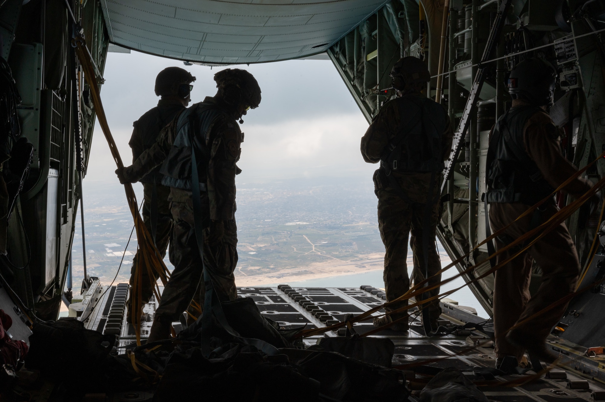Loadmasters aboard a HC-130J complete an airdrop delivering bundles of humanitarian aid over Gaza.