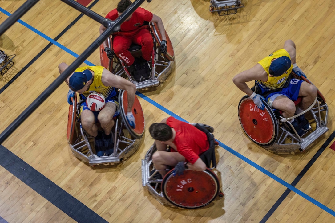 Two U.S. Marine Corps athletes and two Ukrainian athletes using wheelchairs participate in a rugby competition as seen from above.