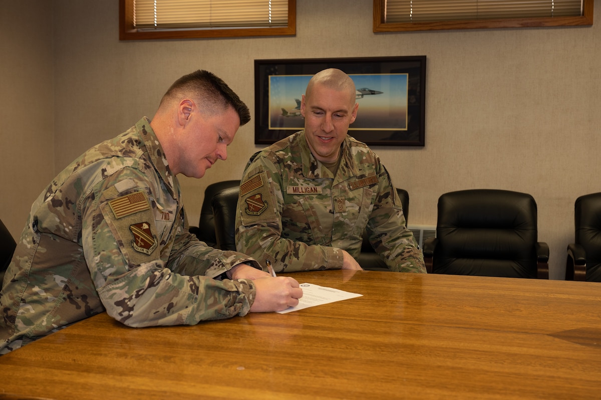 The 354th Fighter Wing commander and command chief sign a memorandum for the Air Force Assistance Fund at Eielson Air Force Base, Alaska.