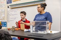 Sybrina Nanez, metrology quality assurance specialist, Code 901, Production Resources Department, at Puget Sound Naval Shipyard & Intermediate Maintenance Facility in Bremerton, Washington, helps a student conduct a neutral buoyancy experiment, Feb. 2, 2024, at Hilder Pearson Elementary School in Poulsbo, Washington. (U.S. Navy photo by Jeb Fach)