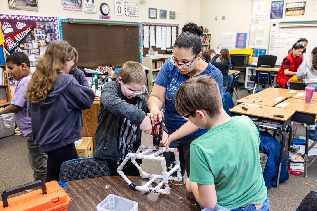 Sybrina Nanez, metrology quality assurance specialist, Code 901, Production Resources Department, at Puget Sound Naval Shipyard & Intermediate Maintenance Facility in Bremerton, Washington, helps students drill holes in an underwater remotely operated vehicle, Feb. 2, 2024, during a STEM program at Hilder Pearson Elementary School in Poulsbo, Washington. (U.S. Navy photo by Jeb Fach)