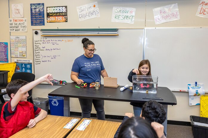 : Sybrina Nanez, metrology quality assurance specialist, Code 901, Production Resources Department, at Puget Sound Naval Shipyard & Intermediate Maintenance Facility in Bremerton, Washington, teaches a group of STEM program students about buoyancy, Feb. 2, 2024, at Hilder Pearson Elementary School in Poulsbo, Washington, by testing to see which objects sink or float. (U.S. Navy photo by Jeb Fach)