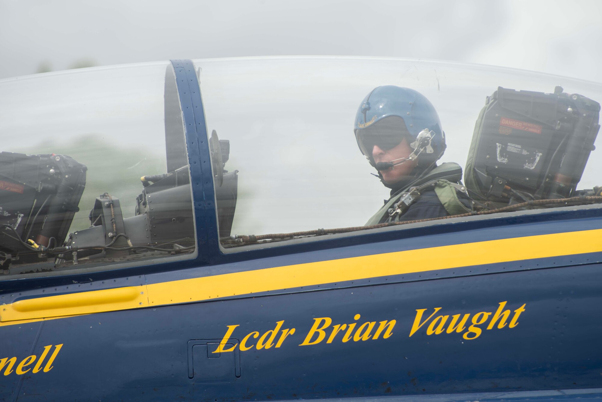 A man sits inside a military jet.