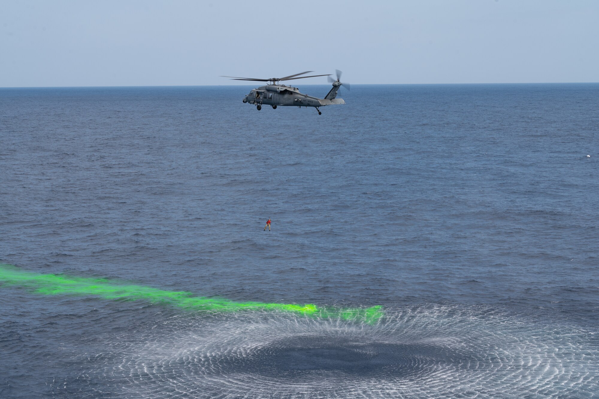 An Airman is lowered from a helicopter.