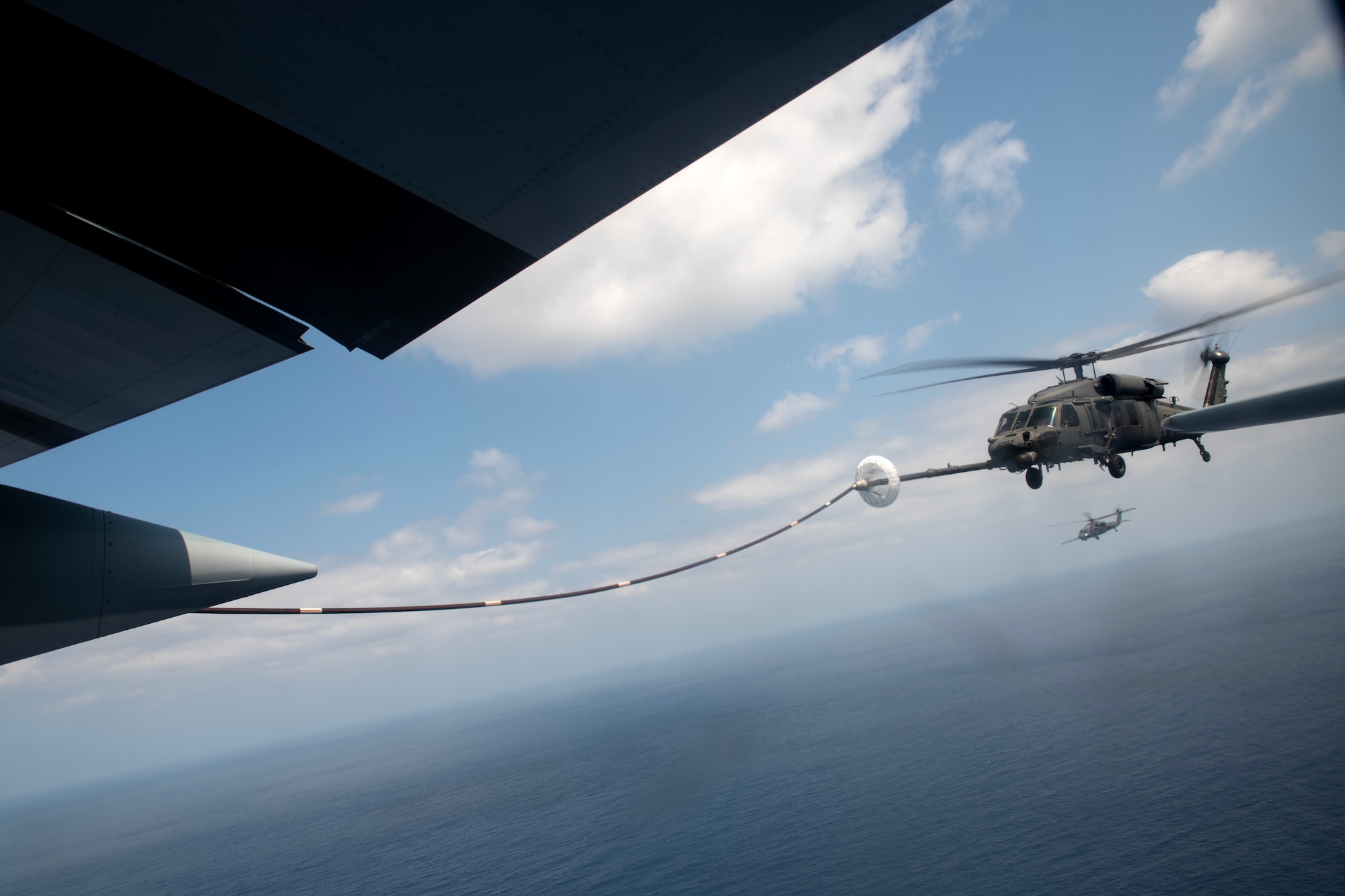 A U.S. Air Force HH-60G Pave Hawk assigned to the 33rd Rescue Squadron conducts helicopter air-to-air refueling with a U.S. Marine Corps KC-130J Super Hercules assigned to Marine Aerial Refueler Transport Squadron (VMGR) 152, during a joint search and rescue training mission over the Pacific Ocean, March 13, 2024. Dual wing-mounted hose and drogue configurations on the KC-130J allow the transfer of up to 300 gallons of fuel per minute to two aircraft concurrently. (U.S. Air Force Photo by Staff Sgt. Jessi Roth)