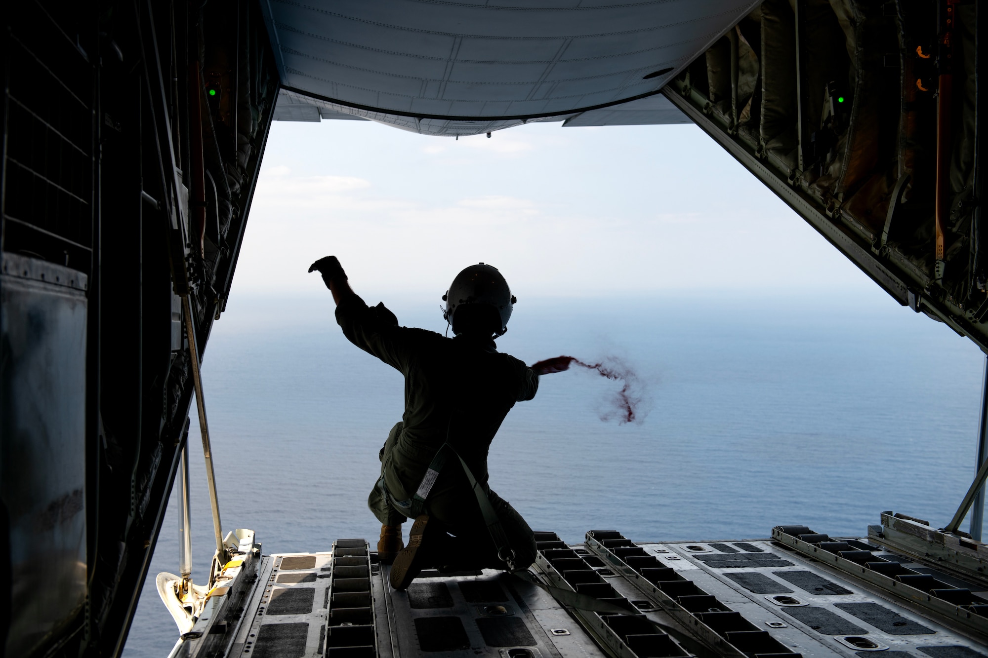 U.S. Marine Corps Cpl. Devon Sanberg, a loadmaster with Marine Aerial Refueler Transport Squadron (VMGR) 152, releases a pack of sea marker dye during a joint search and rescue training mission over the Pacific Ocean, March 13, 2024. The non-toxic sea dye creates a spread of fluorescent green over the water's surface, enhancing visibility for rescue pilots. (U.S. Air Force Photo by Staff Sgt. Jessi Roth)