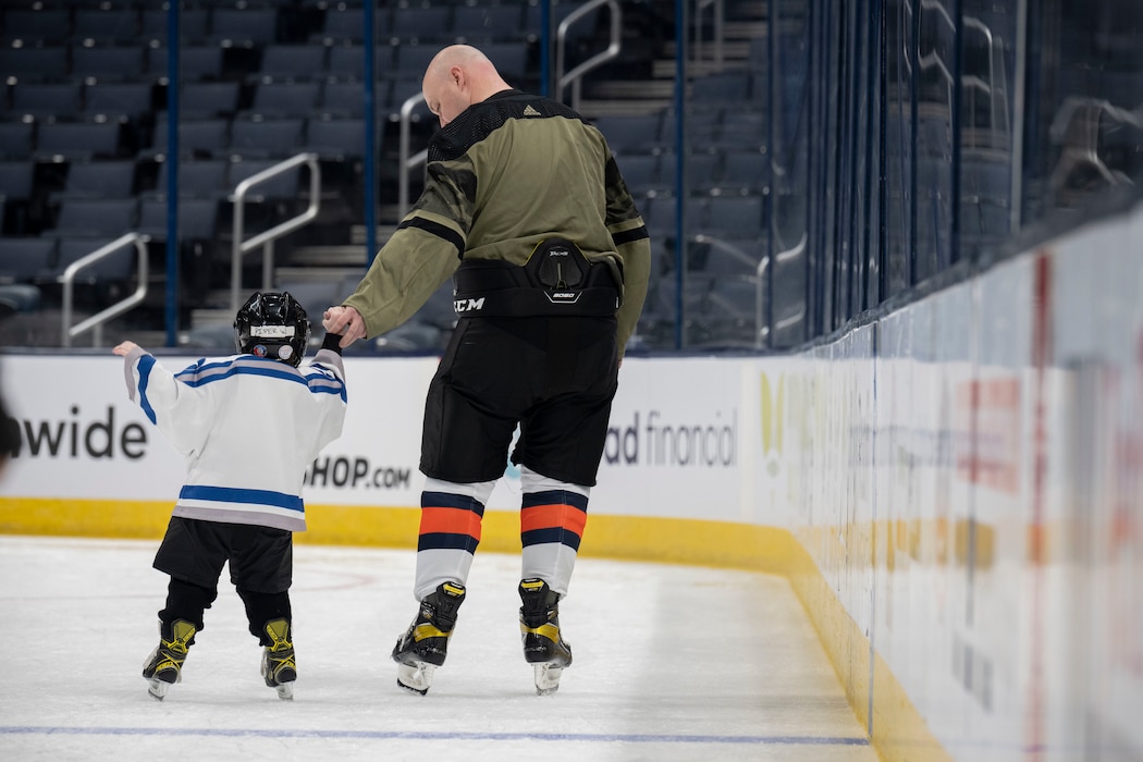Maj. Alex Wyrick, Wright-Patterson Air Force Base Hockey Club member, and his daughter, Piper, hold hands while skating