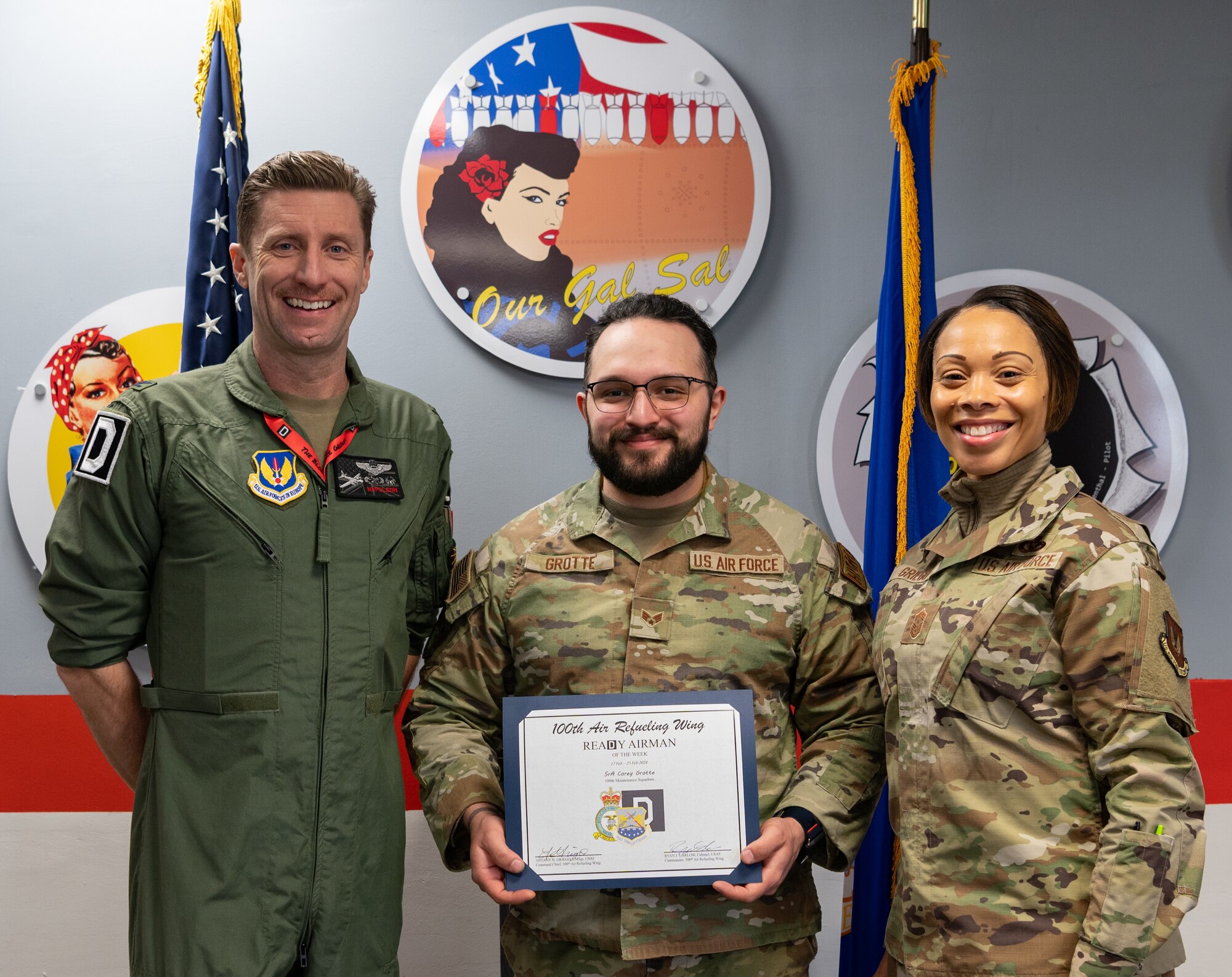 U.S. Air Force Col. Ryan Garlow, left, 100th Air Refueling Wing commander, and Chief Master Sgt. Tiffany Griego, right, 100th ARW command chief, congratulates Senior Airman Corey Grotte, 100th Aircraft Maintenance Squadron hydraulics journeyman, for being the ReaDy Airman of the Week at Royal Air Force Mildenhall, England, March 15, 2024.