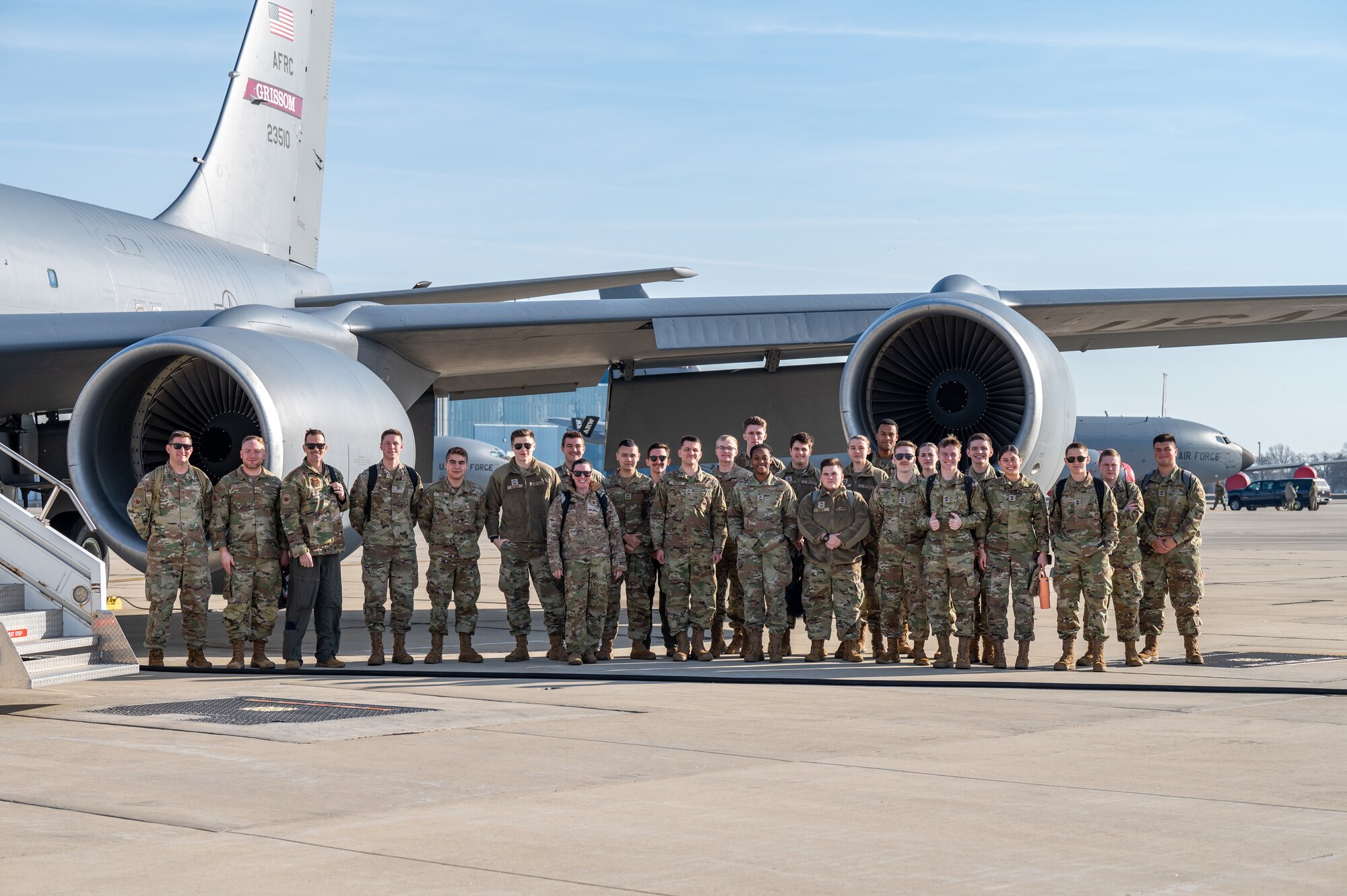 A group of men and women wearing U.S. Air Force uniforms stand in front of a plane.