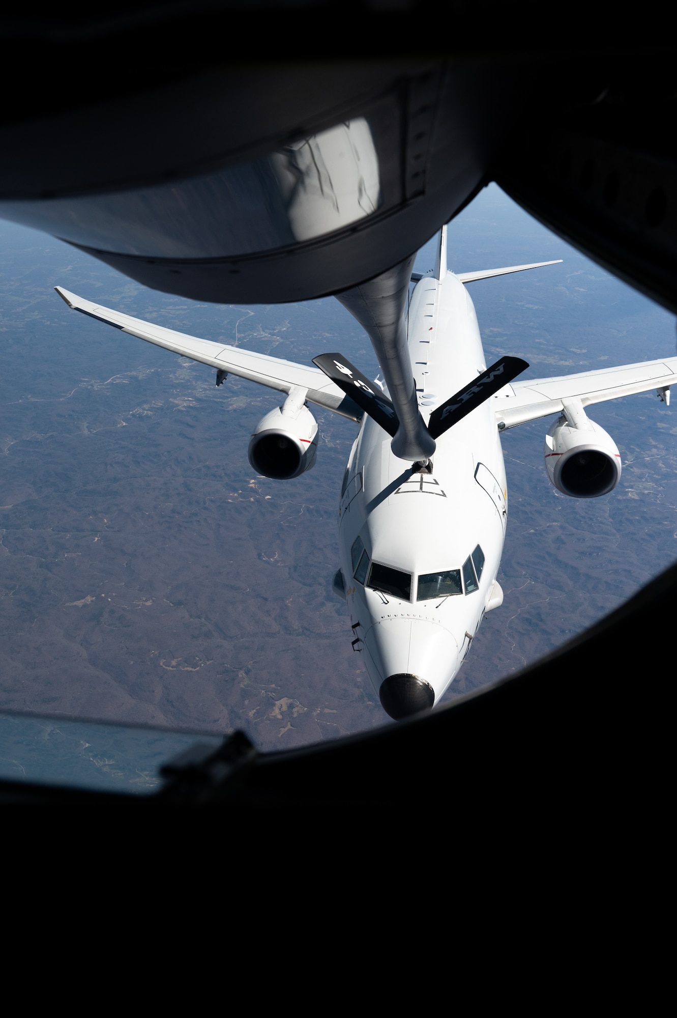 A white airplane, in flight, receives fuel from a fuel line that reads "434 ARW".