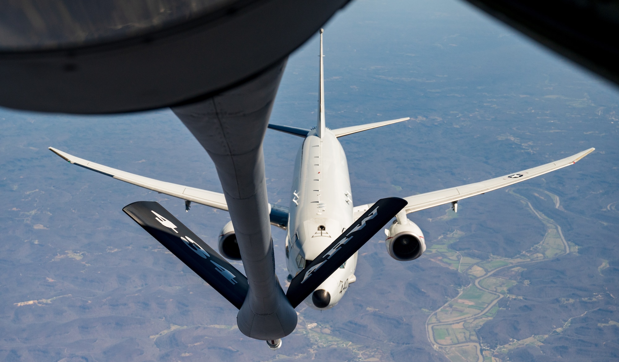 A white airplane, in-flight, is seen below a fuel line that reads "434 ARW".