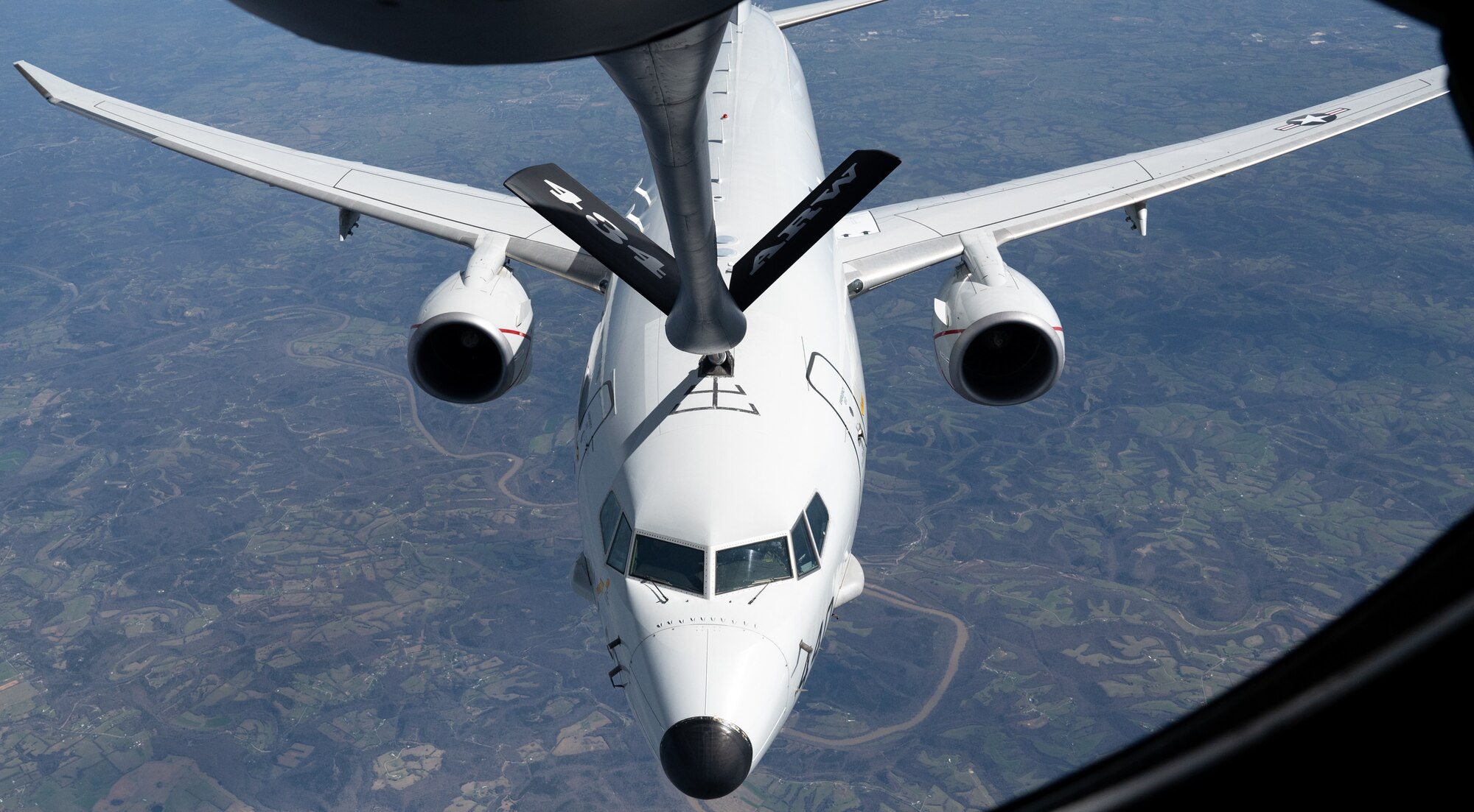 A white aircraft, in flight, receiving fuel from a fuel line that reads "434 ARW".