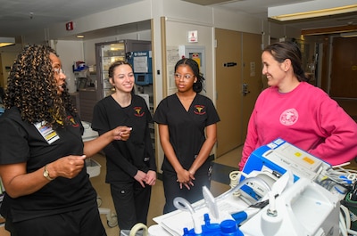 Dr. Angelia Washington, Abigail Brown, and Madison Pankey with Lejeune High School discuss health care delivery with NMCCL Nurse Brittany Chapman (pictured right) in the Intensive Care Unit of Naval Medical Center Camp Lejeune on March 5, 2024. Brown and Pankey are enrolled in the high school’s Health Sciences/Nurse Aide I Program led by Washington, a nurse educator and founder of the program.