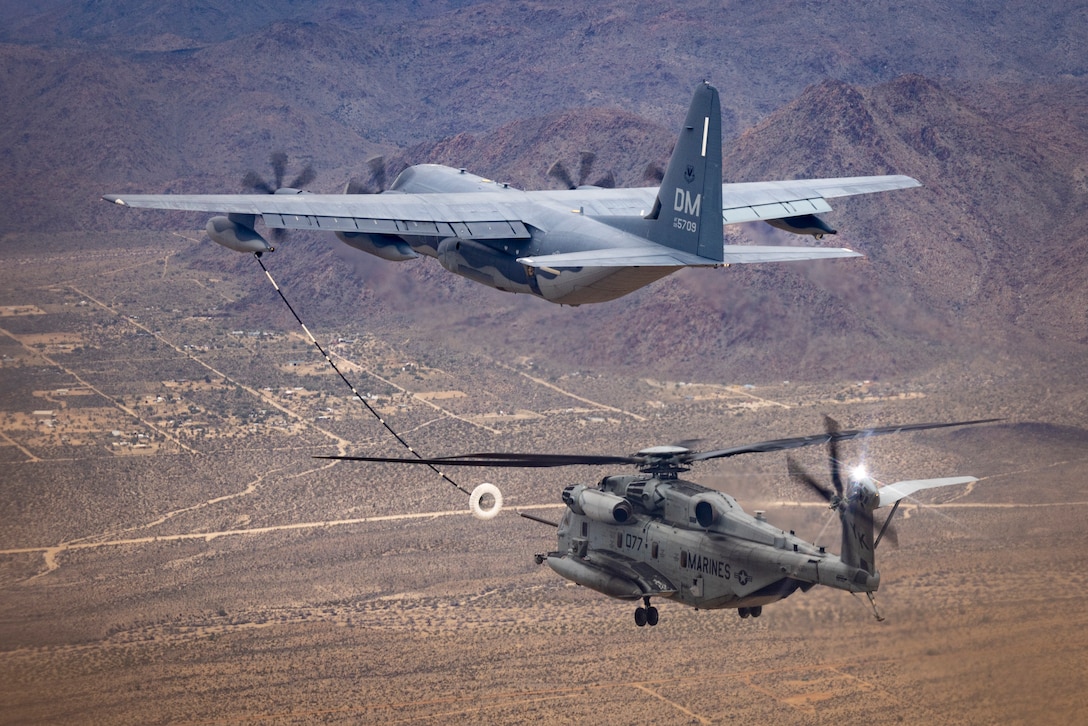 U.S. Marine Corps Cpl. Noah Bueschel, a CH-53E Super Stallion helicopter crew chief with Marine Heavy Helicopter Squadron (HMH) 462, Marine Aircraft Group 16, 3rd Marine Aircraft Wing, surveys the area during joint air-to-air refueling with a U.S. Air Force HC-130J Combat King II assigned to the 79th Rescue Squadron, 563rd Rescue Group, 355th Rescue Wing, near Lake Havasu City, Arizona, Feb. 26, 2024. The “Heavy Haulers” of HMH-462 conducted air-to-air refueling during unit deployment training to enhance aircrew proficiency and increase combat effectiveness. (U.S. Marine Corps photo by Lance Cpl. Jackson Rush)