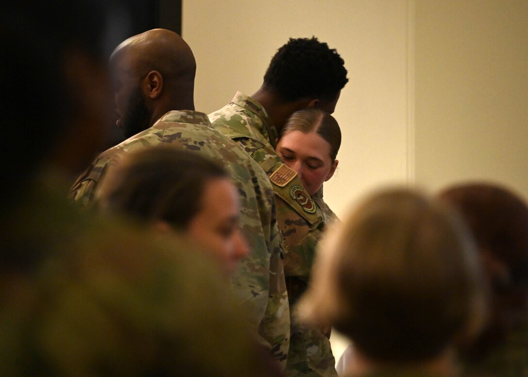 Man in military uniform hugs a woman in a military uniform.