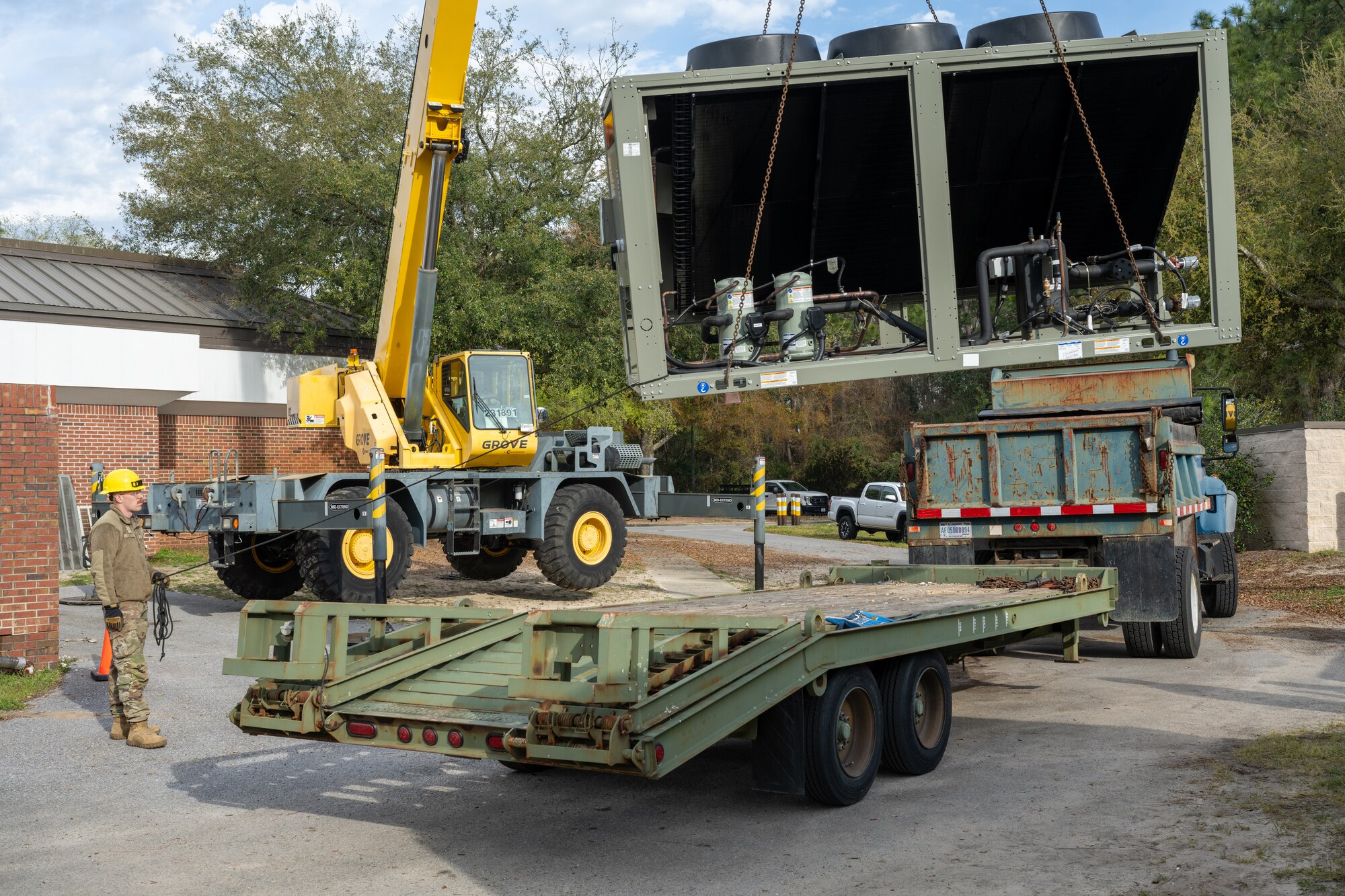 U.S. Air Force Senior Airman Bryon Eastes, a 1st Special Operations Civil Engineer Squadron pavement and construction equipment apprentice, helps guide a crane while replacing a chiller at Hurlburt Field, Florida, March 13, 2024. Replacing the chiller provides the Chapel with a more reliable air conditioning system to ensure Air Commandos and families will be comfortable while visiting the Chapel during the summer months. (U.S. Air Force photo by Senior Airman Alysa Calvarese)