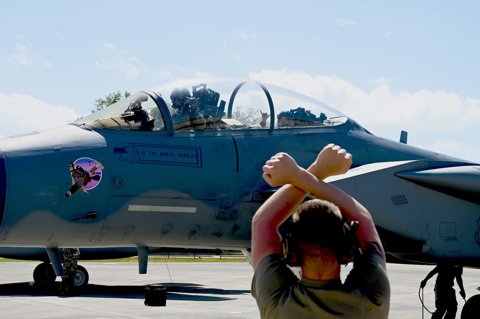 A U.S. Air Force crew chief from the 173rd Fighter Wing at Kingsley Field, Ore., directs an F-15 Eagle back to the ramp parking during Sentry Luau at Joint Base Pearl Harbor-Hickam, Feb. 26, 2024. Approximately 20 Airmen from Kingsley Field received familiarization flights while at JBPHH.