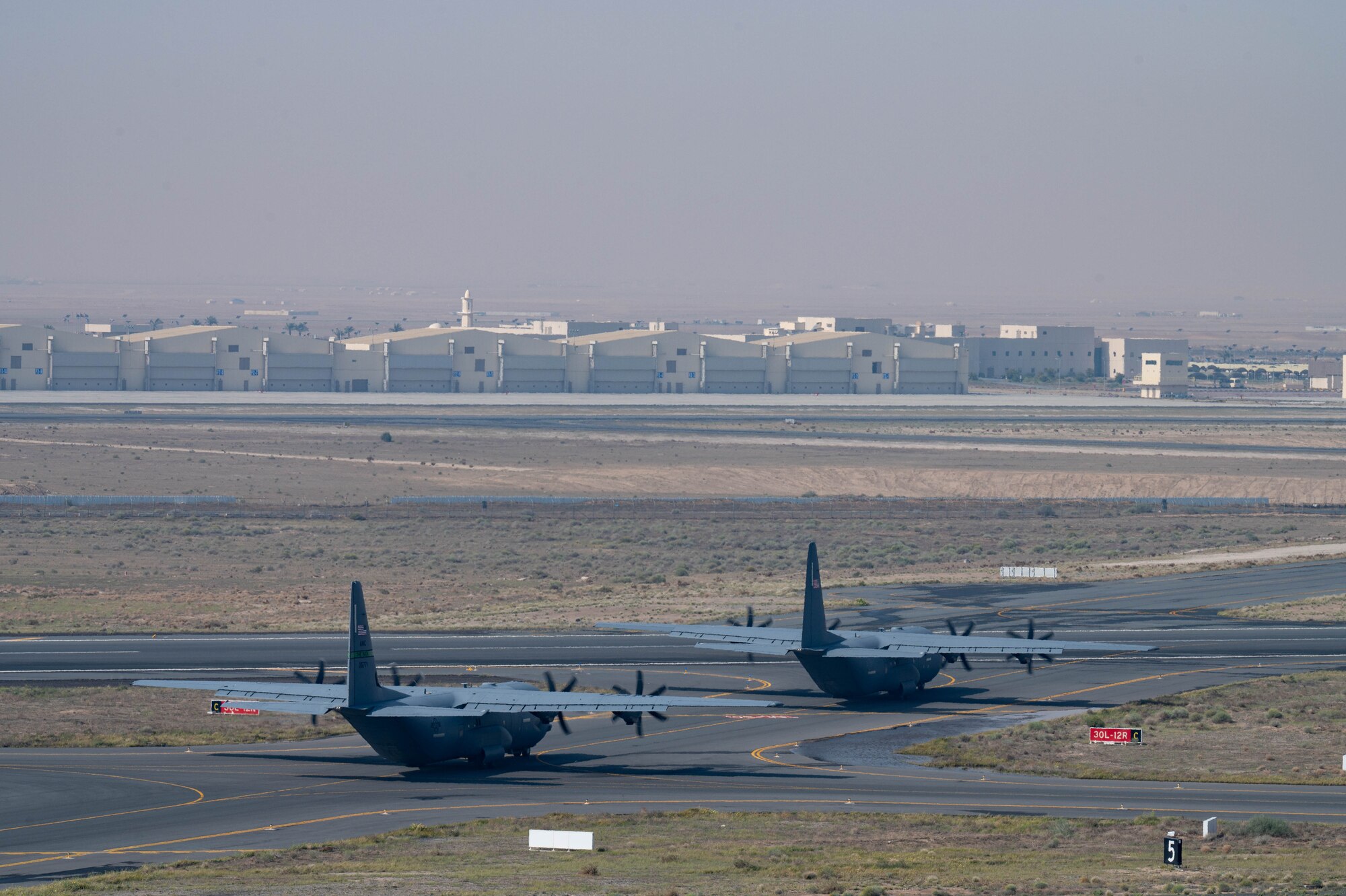 Two C-130J aircraft loaded with humanitarian aid bound for airdrop over Gaza taxi in preparation for take off.