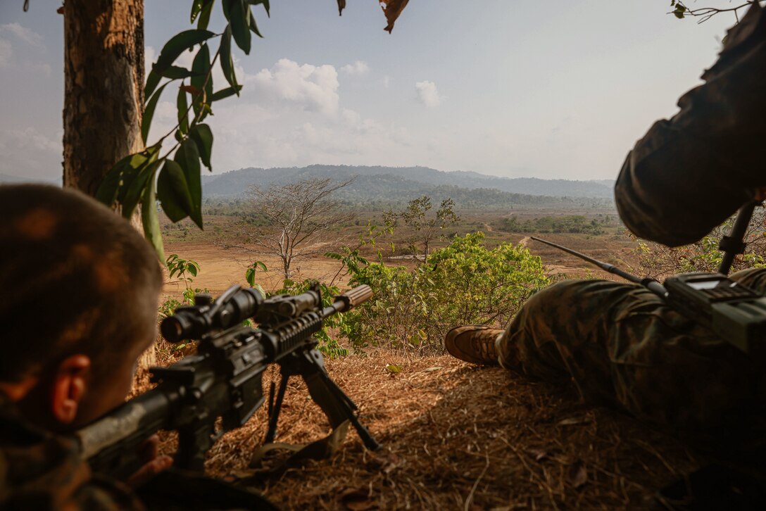 U.S. Marine Corps 1st Lt. Joseph Maisonville, left, a platoon commander assigned to Charlie Company, Battalion Landing Team 1/5, 15th Marine Expeditionary Unit, sights in on simulated enemy targets with an M27 Infantry Automatic Rifle from a fire support team position during a call for fire mortar range as part of Exercise Cobra Gold in Chanthaburi province, Thailand, March 3, 2024. Cobra Gold, now in its 43rd iteration, demonstrates ongoing readiness to operate throughout the region in support of allies and partners to ensure a free and open Indo-Pacific. (U.S. Marine Corps photo by Cpl. Aidan Hekker)