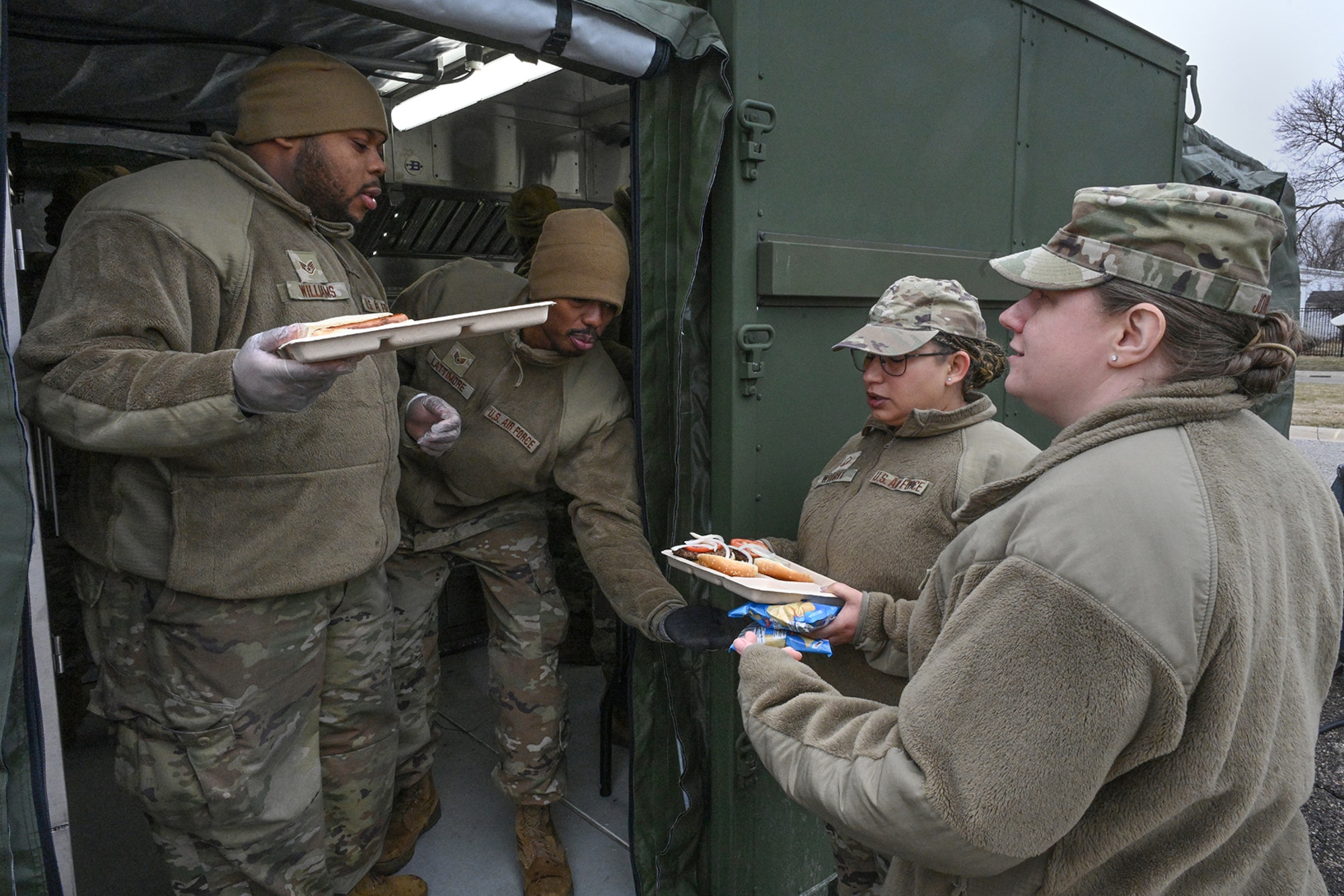 U.S. Air Force Staff Sgt. Devonte Williams, left, and Staff Sgt. Dontrell Lattimore, both services craftsmen with the 127th Force Support Squadron, serve freshly cooked hot-A meals to Master Sgt. Sarah Wright and Tech. Sgt. Katherine Johnson of the 127th Wing.