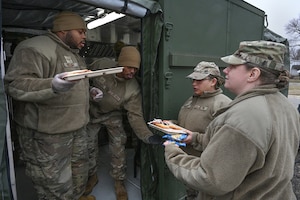 U.S. Air Force Staff Sgt. Devonte Williams, left, and Staff Sgt. Dontrell Lattimore, both services craftsmen with the 127th Force Support Squadron, serve freshly cooked hot-A meals to Master Sgt. Sarah Wright and Tech. Sgt. Katherine Johnson of the 127th Wing.