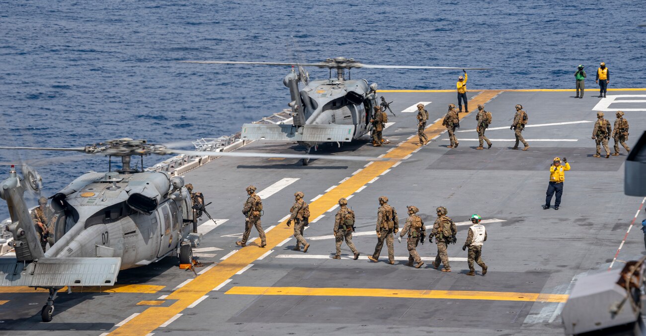 Marines from the 31st Marine Expeditionary Unit board MH-60S Sea Hawk helicopters from Helicopter Sea Combat Squadron (HSC) 25 on the flight deck of the forward-deployed amphibious assault carrier USS America (LHA 6)