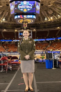 Female U.S. Army Soldier in AGSU Uniform poses on the sidelines of a bacsketball court