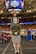 Female U.S. Army Soldier in AGSU Uniform poses on the sidelines of a bacsketball court