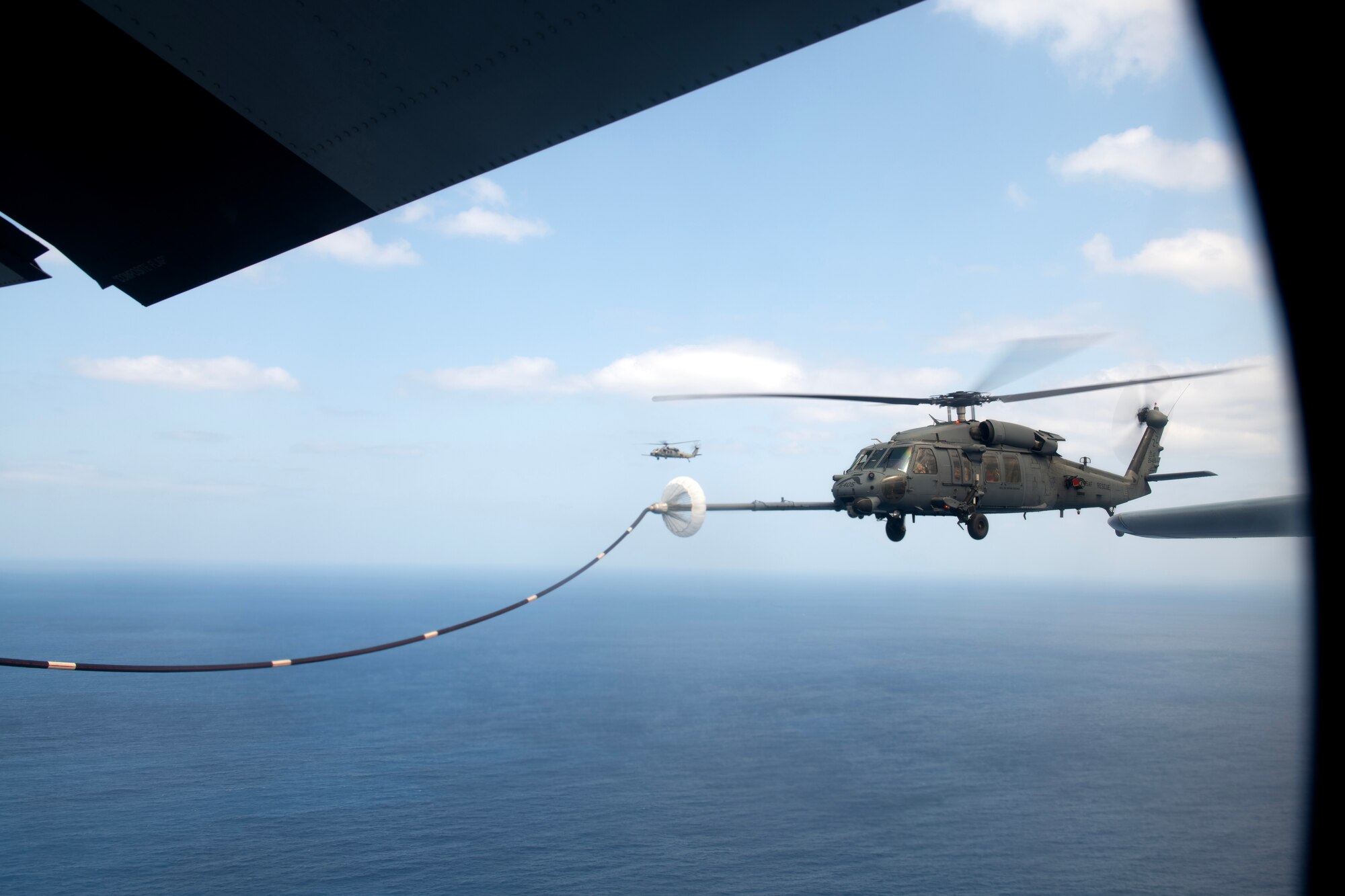 A U.S. Air Force HH-60G Pave Hawk assigned to the 33rd Rescue Squadron conducts helicopter air-to-air refueling with a U.S. Marine Corps KC-130J Super Hercules assigned to Marine Aerial Refueler Transport Squadron (VMGR) 152, during a joint search and rescue training mission over the Pacific Ocean, March 13, 2024. Dual wing-mounted hose and drogue configurations on the KC-130J allow the transfer of up to 300 gallons of fuel per minute to two aircraft concurrently. (U.S. Air Force Photo by Staff Sgt. Jessi Roth)