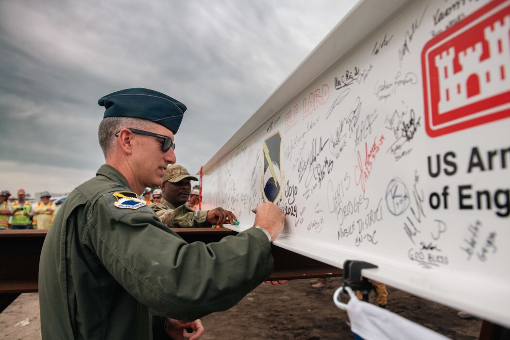 Service members sign a support beam.