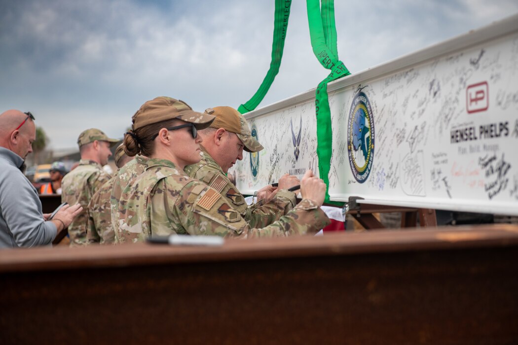 Service members sign a support beam.