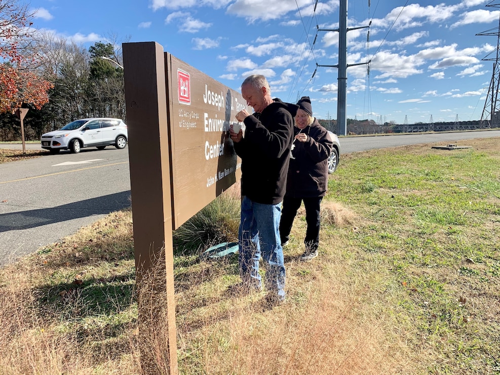 Volunteers painting the Joseph S.J. Tanner Environmental Education Center wooden sign.