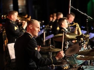 man wearing u.s. army uniform plays the drums.
