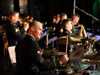 man wearing u.s. army uniform plays the drums.