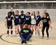 group of girls in volleyball uniform pose for a photo.