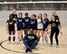 group of girls in volleyball uniform pose for a photo.