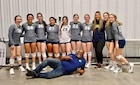 group of girls in volleyball uniform pose for a photo.