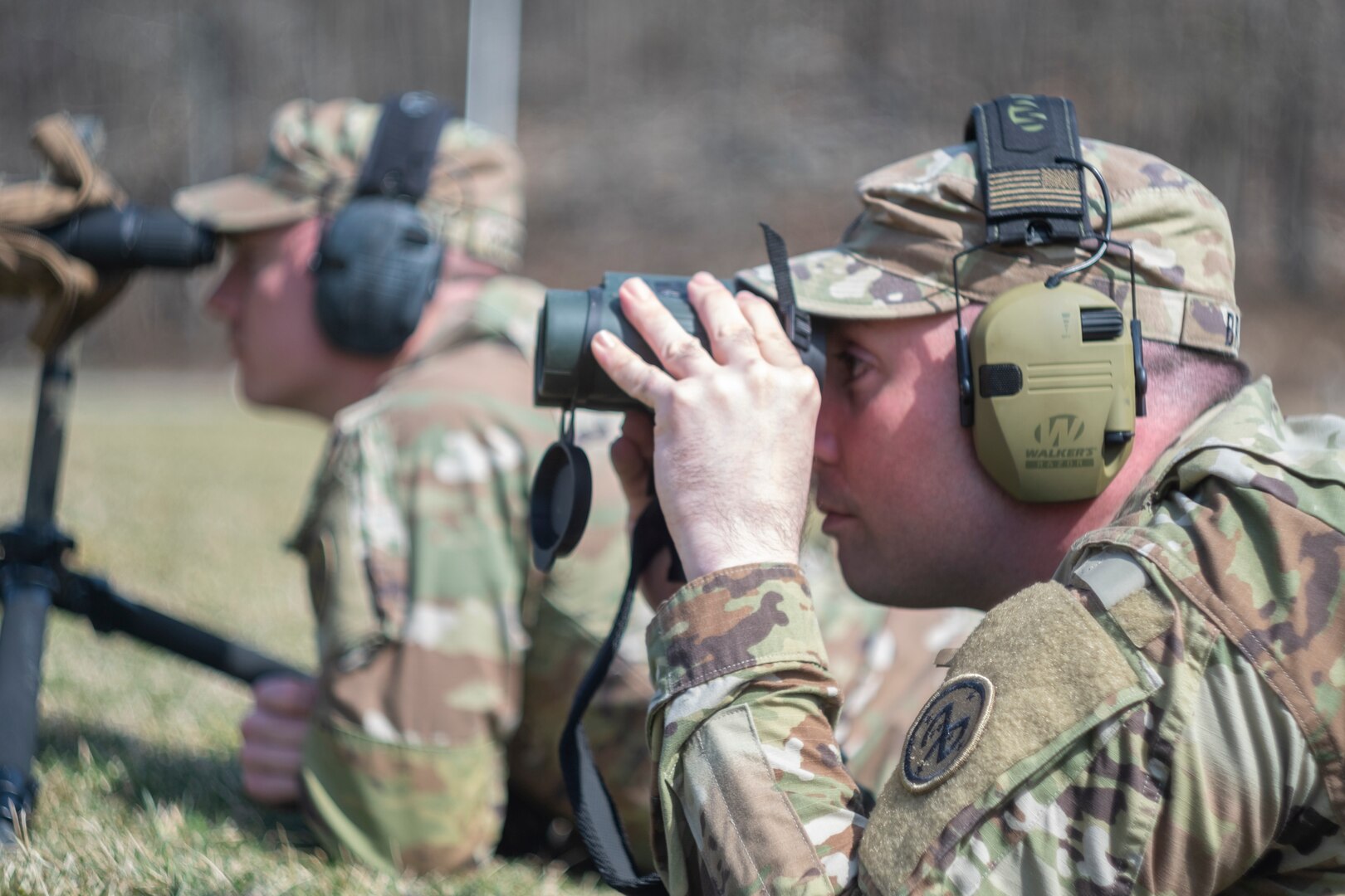 U.S. Army Staff Sgt. Ryan Brum, a squad leader assigned to Charlie Company, 1st Battalion, 182nd Infantry Regiment, uses a pair of binoculars to view a competitor target during the 2024 Logan-Duffy Marksmanship Competition at Camp Smith Training Site in Peekskill, New York, March 13, 2024. The Logan-Duffy Marksmanship Competition is an annual shooting match between 1st Battalion, 69th Infantry Regiment, and 1st Battalion, 182nd Infantry Regiment.