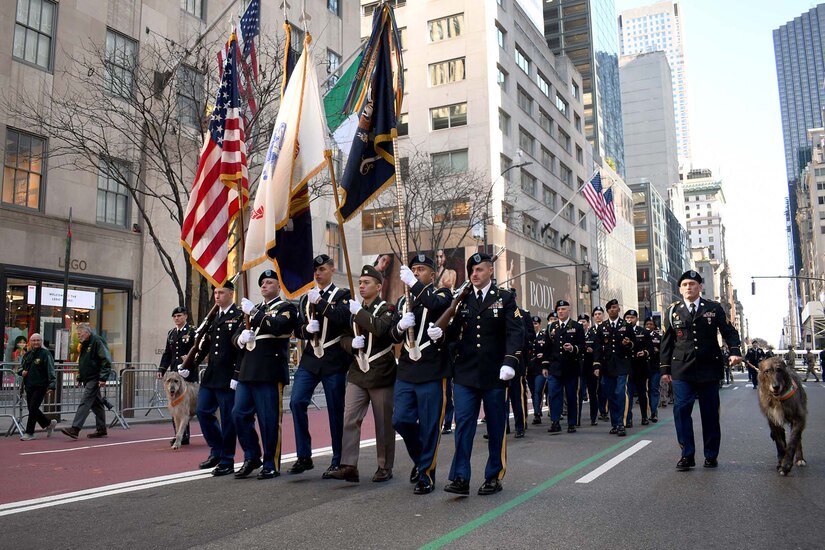 Soldiers holding flags lead a parade.