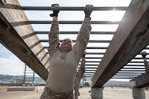 U.S. Marine Corps Recruit Lesile Serna, with Charlie Company, 1st Recruit Training Battalion, navigates the arm stretch obstacle during a confidence course training event at Marine Corps Recruit Depot San Diego, California, March 11, 2024.  The confidence course is designed to challenge recruits physically and mentally through the execution of obstacles that require strength, balance, and determination. (U.S. Marine Corps photo by Cpl. Sarah M. Grawcock)