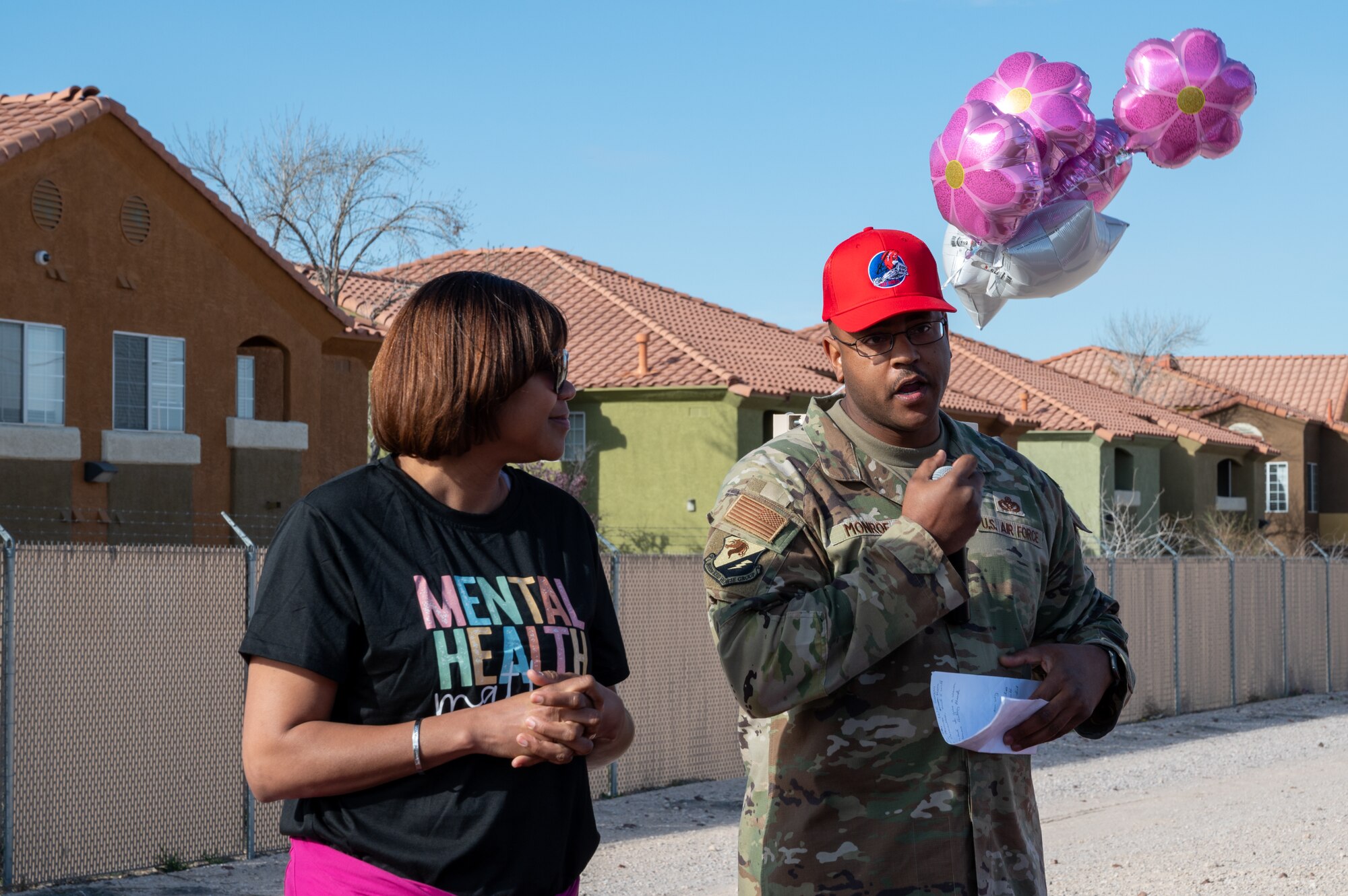 U.S. Air Force Chief Master Sgt. Adrienne Warren, Command Chief Master Sergeant of the 99th Air Base Wing, left, listens to Senior Master Sgt. Christopher Monroe, chairman of the Nellis Special Observance Committee, assigned to 820th Red Horse Squadron, as he introduces the Women Everywhere Walk at Nellis Air Force Base, Nevada, March 7, 2024.