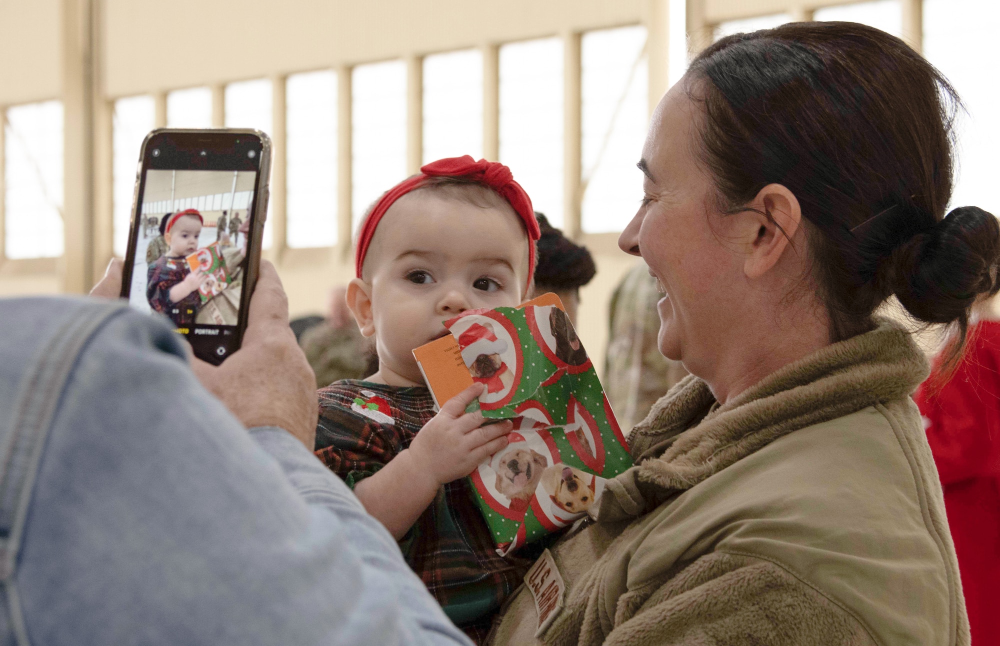 This is a photo of a US AFRC traditional Reservists holding a young child and smiling at them while their photo is being taken on a cellular device.