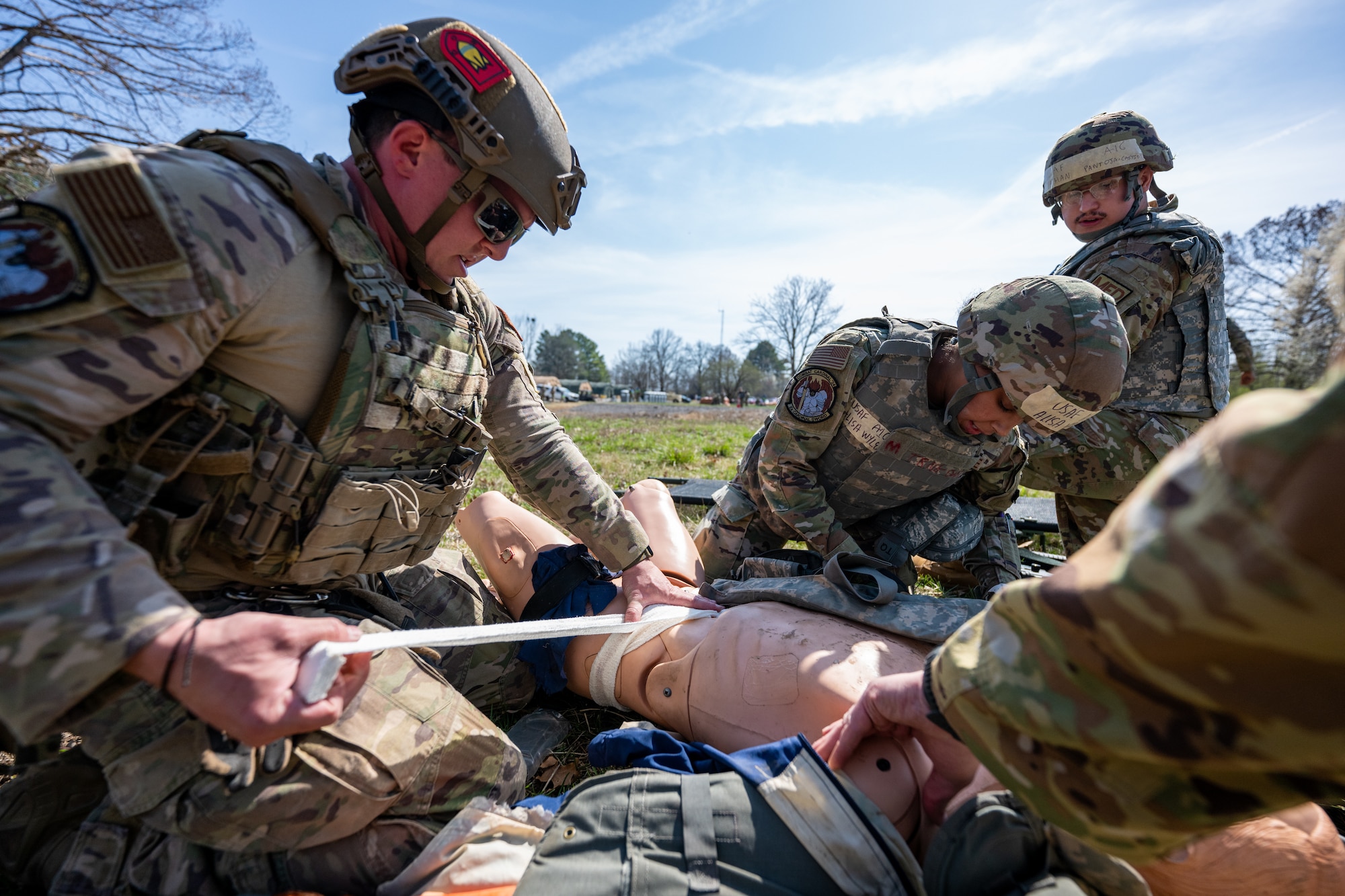 Airmen apply a tourniquet and perform tactical field care to a mannequin.