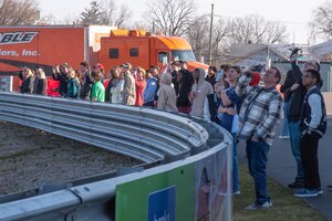 Group of students standing around a horseshoe shaped barrier.