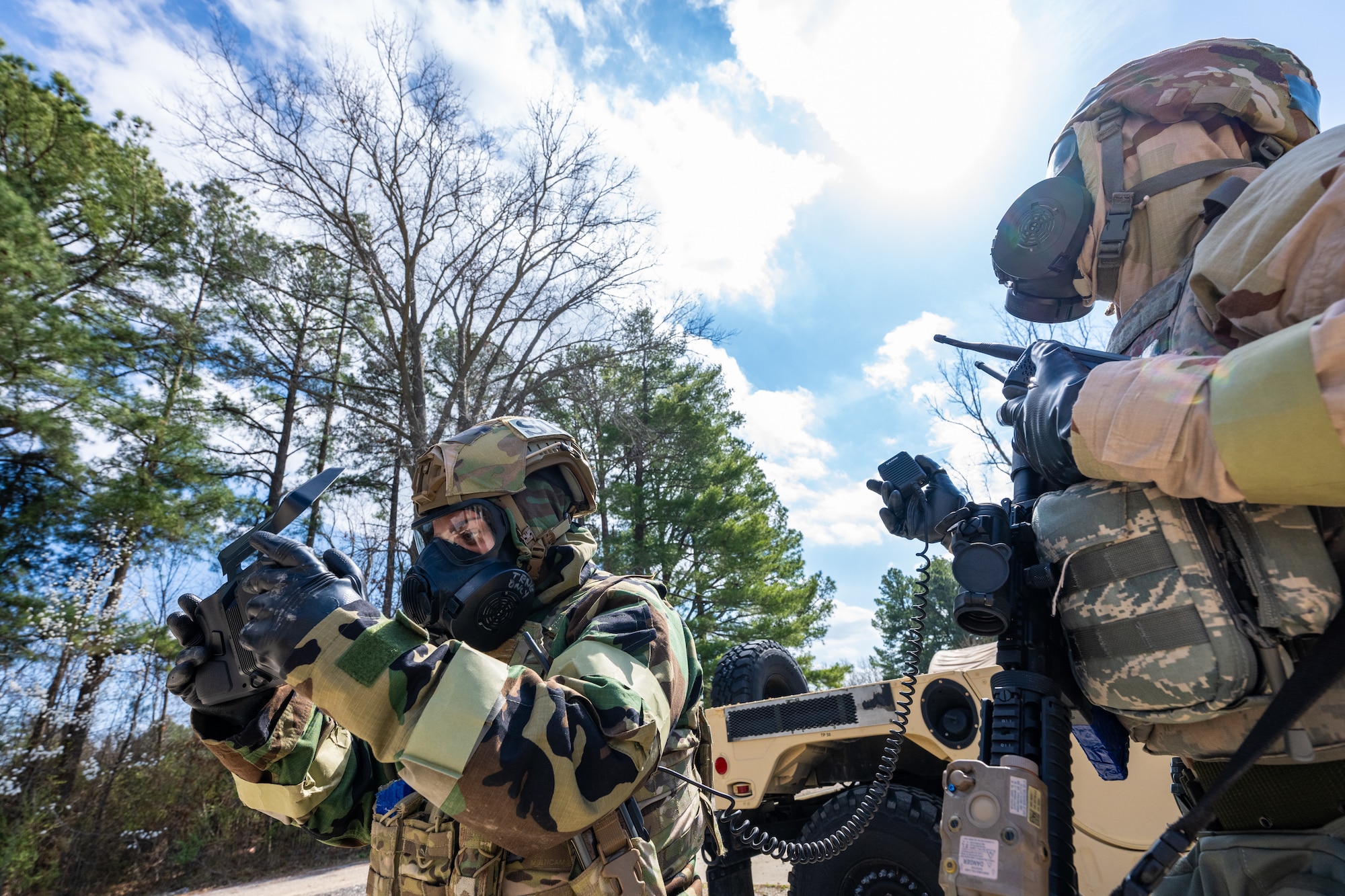 Airmen pilot a drone while wearing protective gear.