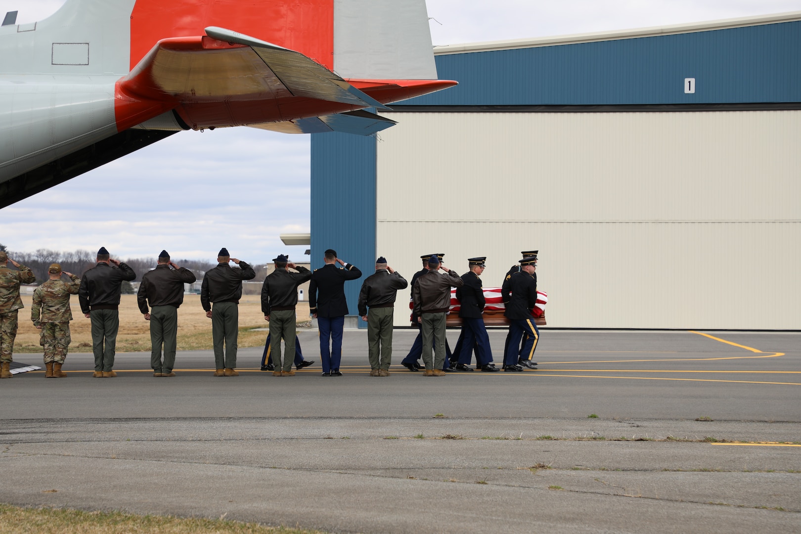 New York Air National Guard Soldiers and Airmen salute as a  New York Army National Guard Honor Guard team carries the remains of  New York Army National Guard Chief Warrant Officer 2 Casey Frankoski from a 109th Airlift Wing LC-130  to a hearse at the Army Aviation Support Facility in Latham, New York, March 18, 2024. Frankoski and Chief Warrant Officer 2 John M. Grassia III were killed in a helicopter crash in Texas March 8, 2024.