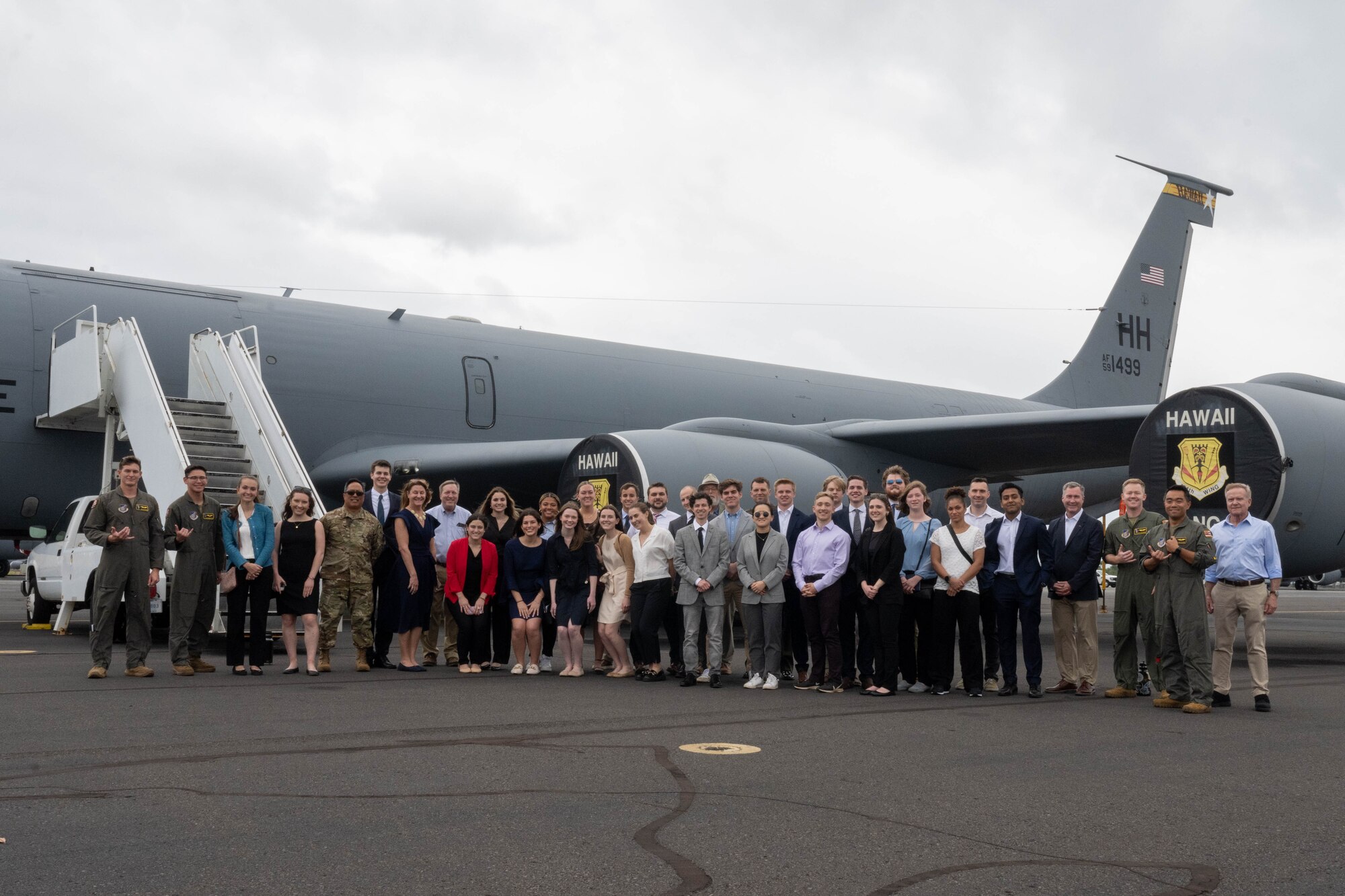 Students stand for group photo in front of an aircraft.