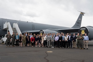 Students stand for group photo in front of an aircraft.