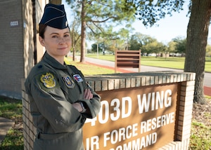 Woman pilot standing outdoors in front of 403rd Wing sign