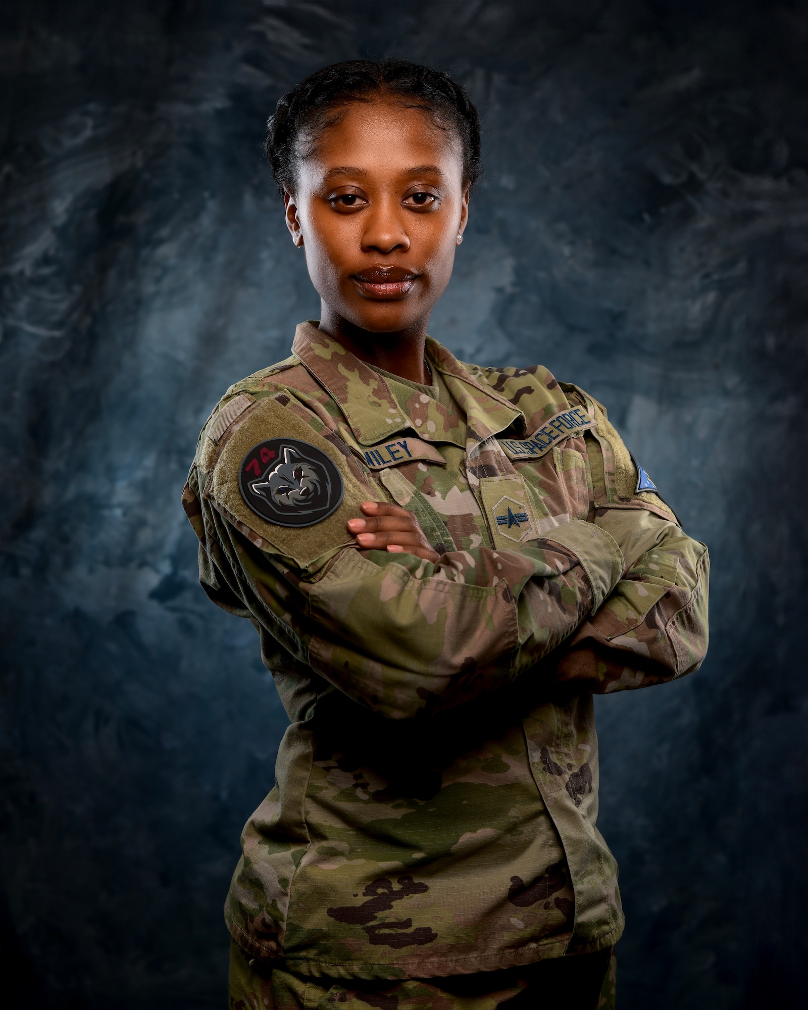 U.S. Space Force Spc. 3 Shayla Wiley, 74th Intelligence, Surveillance and Reconnaissance poses in front of a blue background.